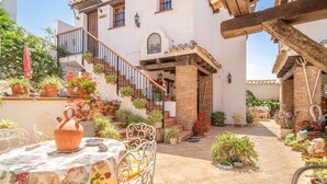 A courtyard with a table set for dining, surrounded by potted plants and a staircase leading to a building. - 1 bedroom cozy apartment in Mondron (Mondron)