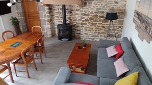 Una sala acogedora con pared de piedra, una mesa de comedor de madera, un sofá y una chimenea.