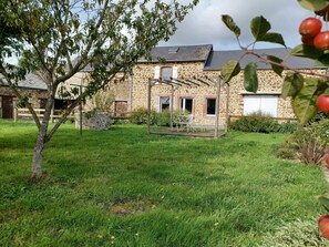 Un bâtiment en pierre doté d’un patio couvert et d’une cour gazonnée.