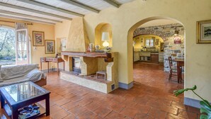 Amplia sala de estar con chimenea, una mesa de comedor y una cocina visible a través de un arco.
