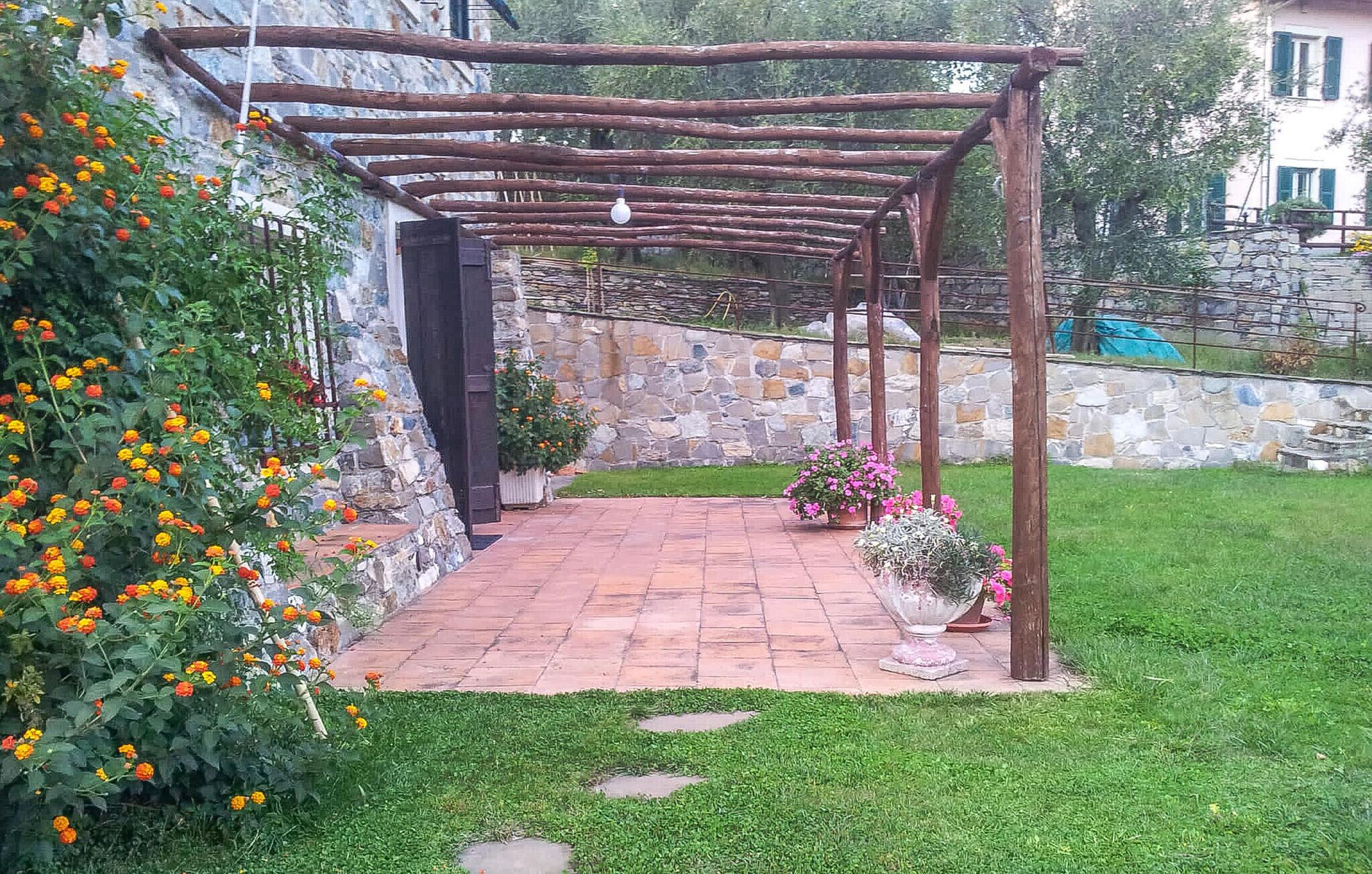 Un jardin agrémenté d’une pergola, d’un mur en pierre et de plantes en pot.