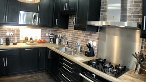 A modern kitchen with dark cabinets, a stainless steel range hood, and a wooden countertop. - Perrosian villa with Jacuzzi, Sauna, Hammam, Home Cinema (Perros-Guirec)