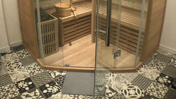 A glass-enclosed sauna with a wooden bench and a small wooden table. - Perrosian villa with Jacuzzi, Sauna, Hammam, Home Cinema (Perros-Guirec)