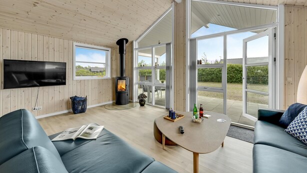 A modern living room with a flat-screen TV, a fireplace, and a large glass door leading to an outdoor area. - 3 bedroom amazing home in Tarm (Tarm)