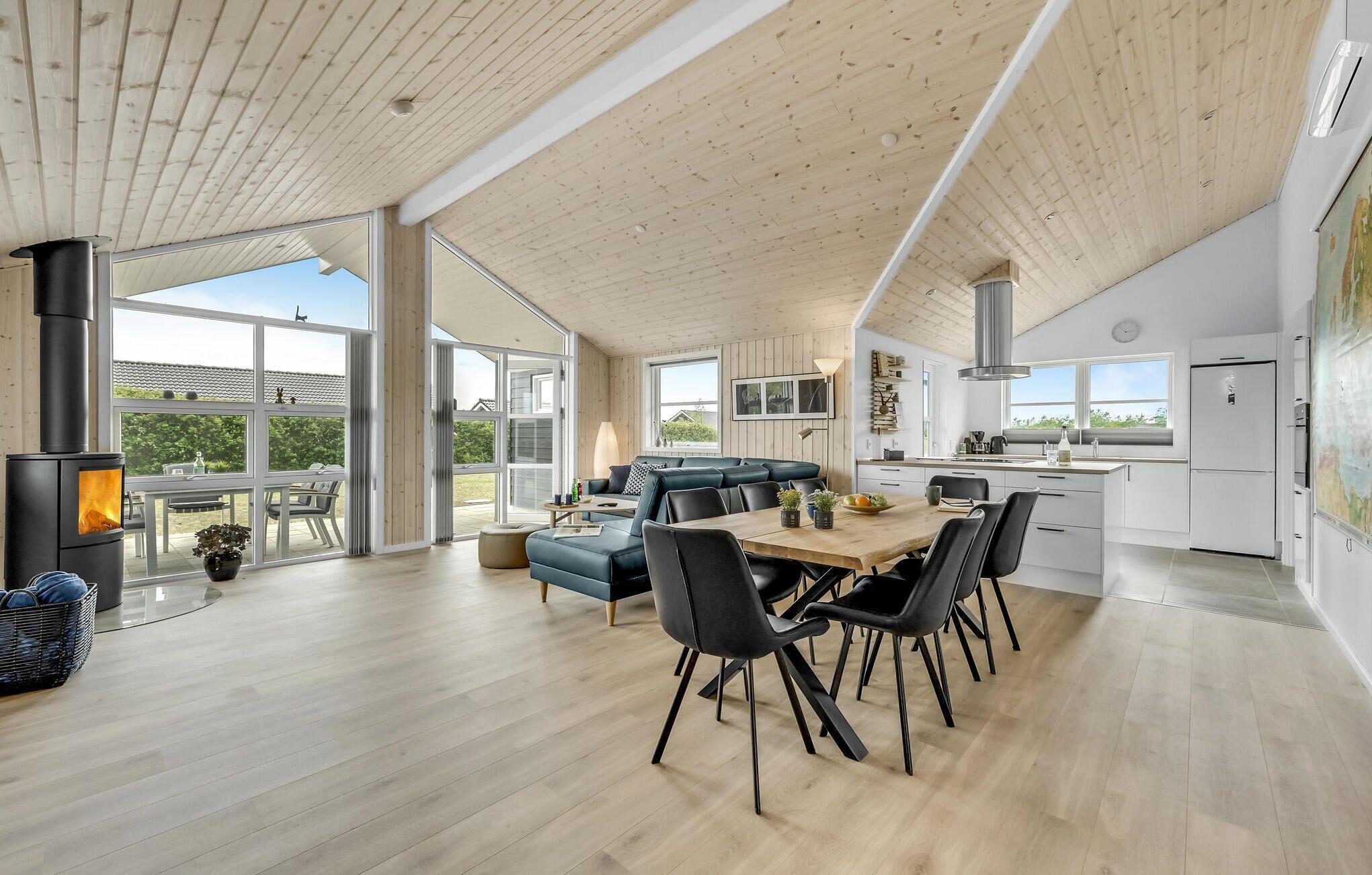 A spacious living area with a large wooden ceiling, a built-in fireplace, and a dining table with chairs.
