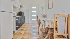 A compact kitchen with a refrigerator, microwave, and cabinets. There is a dining table with chairs and a door leading to another room.