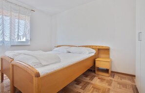 Ein Einzelbett mit Holzrahmen und einem kleinen Nachttisch aus Holz.