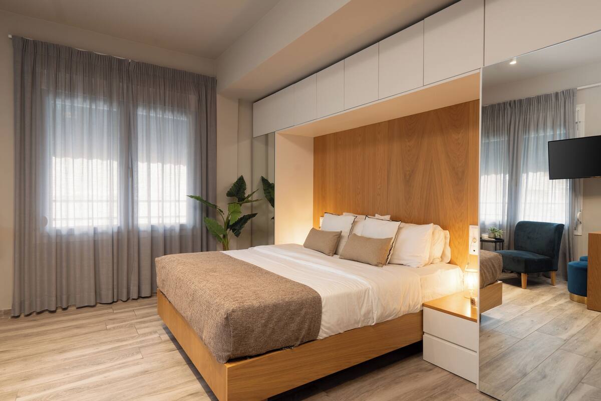 Ein modernes Schlafzimmer mit einem hölzernen Bett, einem Nachttisch, einem Fernseher und einem Sessel.