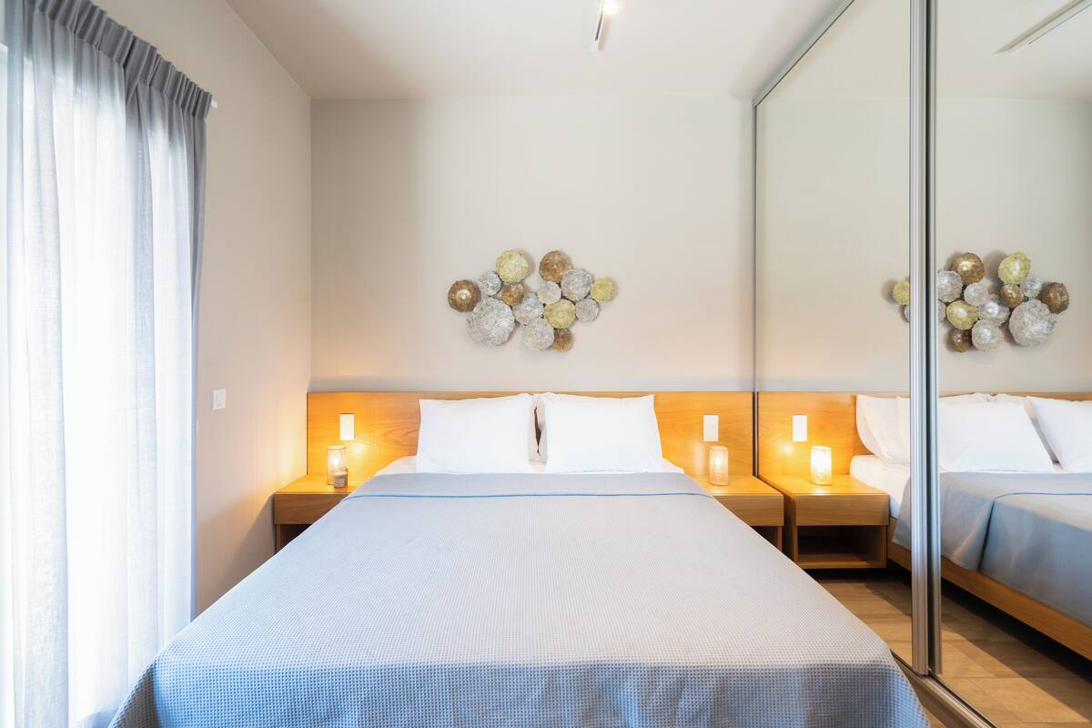 Ein Hotelzimmer mit einem großen Bett, zwei Nachttischen mit Lampen, einem Spiegel und einer Wanddekoration.