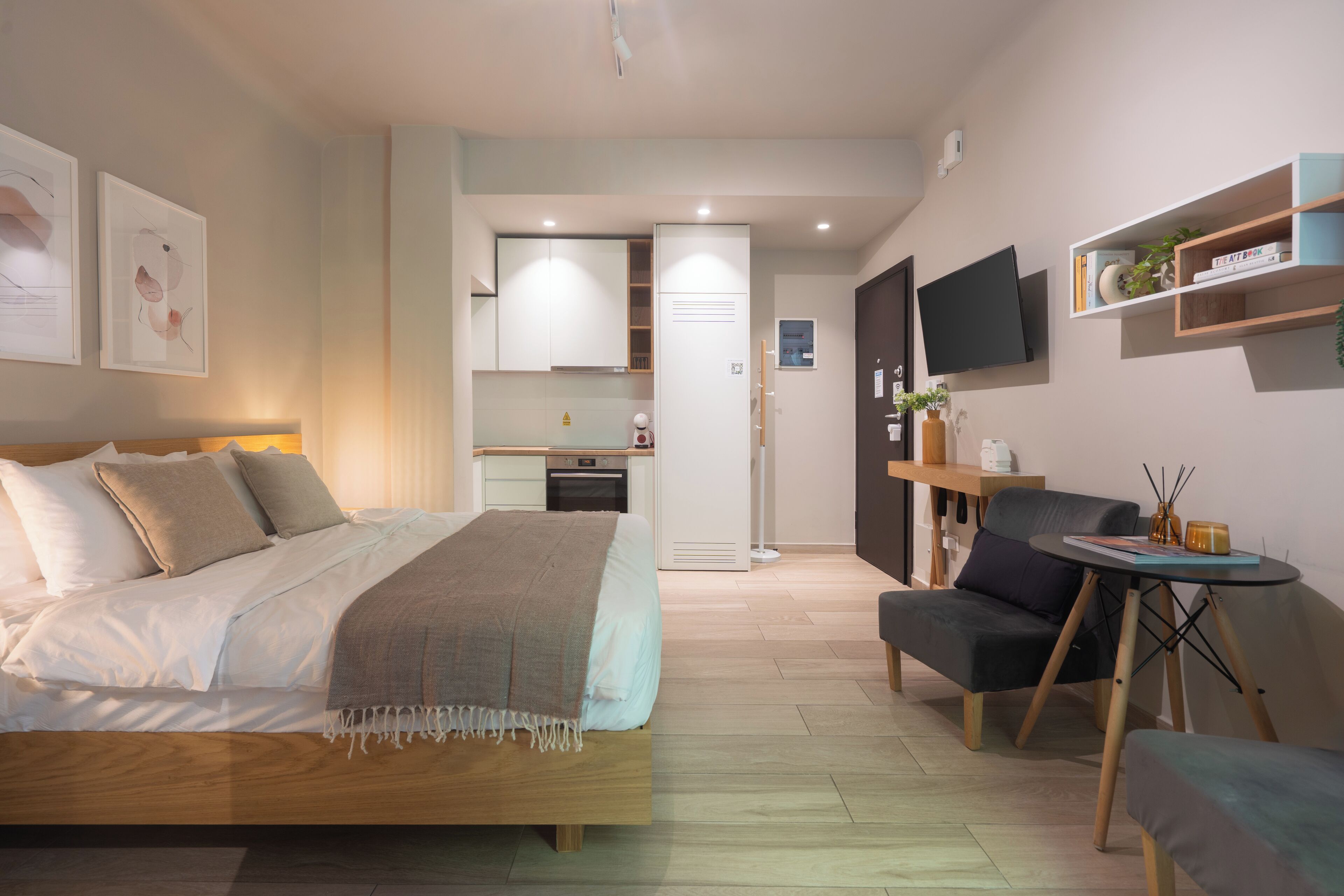 Habitació d'hotel moderna amb un llit, un escriptori, una cadira, un televisor i una taula petita.