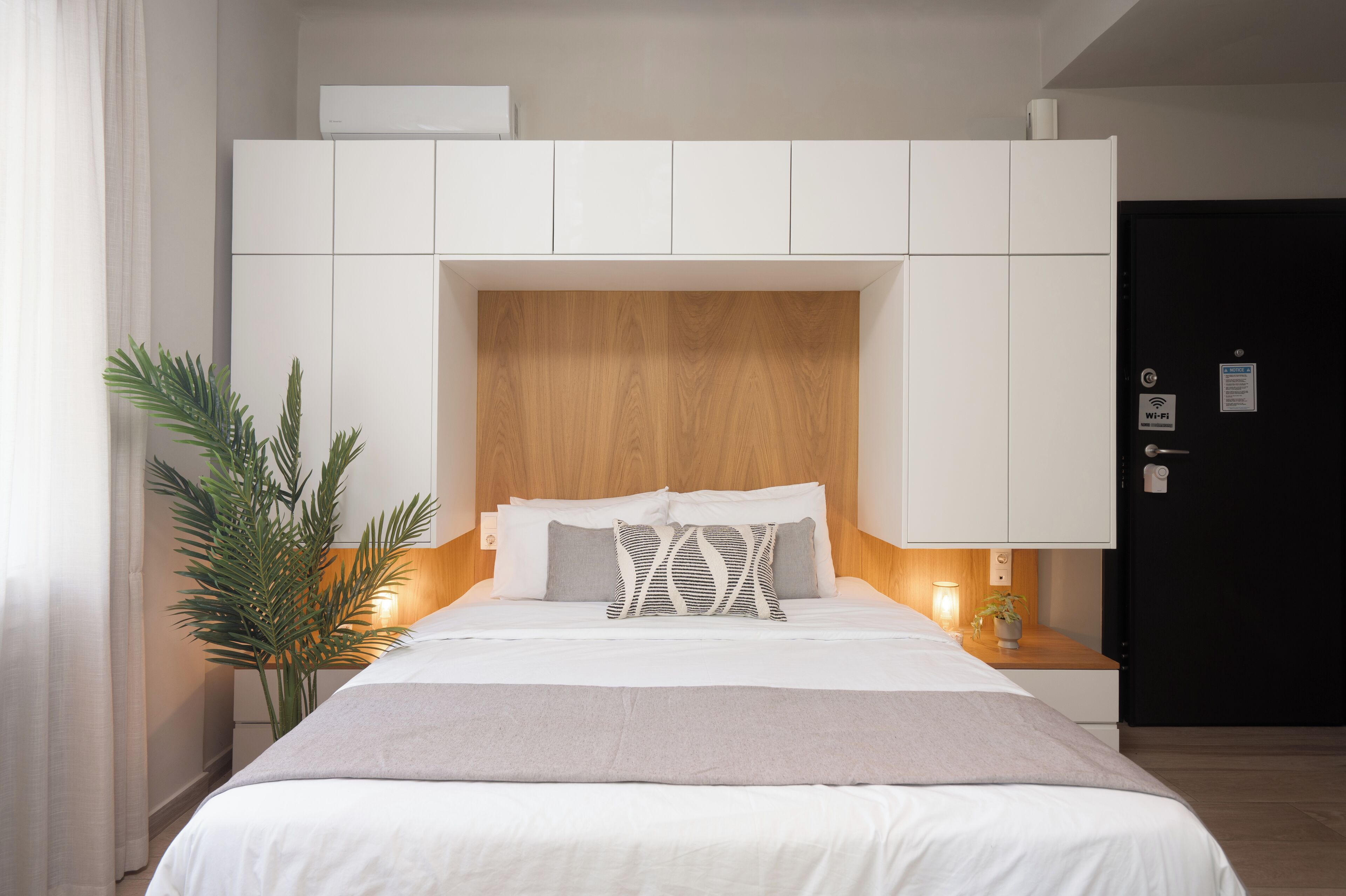 A neatly arranged hotel room with a large bed, a wooden headboard, and a white wardrobe.