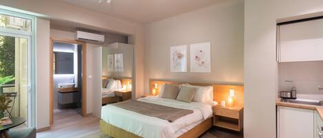 A modern bedroom with a large bed, bedside tables, a built-in wardrobe, and a small kitchenette.