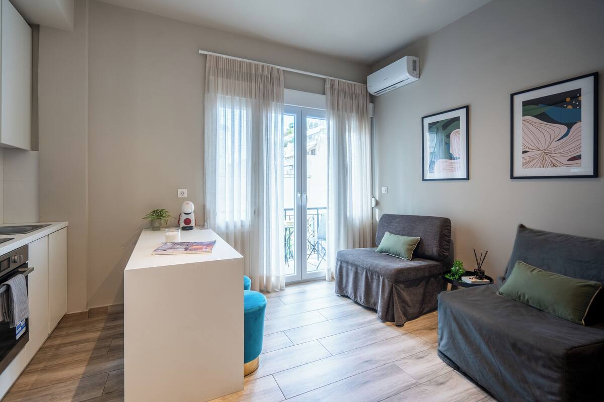 Ein modernes Wohnzimmer mit einer Couch, einem Sessel, einem Couchtisch und einer Küchenzeile mit Spüle und Herd.