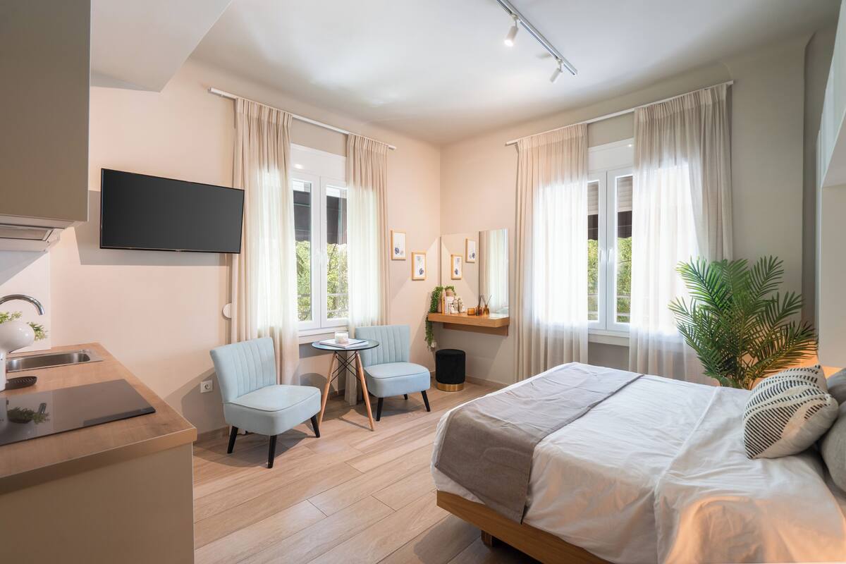 Ein modernes Hotelzimmer mit Bett, Schreibtisch, Stuhl und Fernseher.