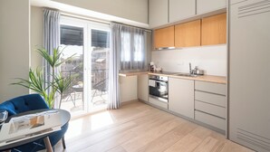 Een moderne keuken met een inbouwoven, een spoelbak en houten kastjes. Er is een eethoek met een blauwe stoel en een tafel.