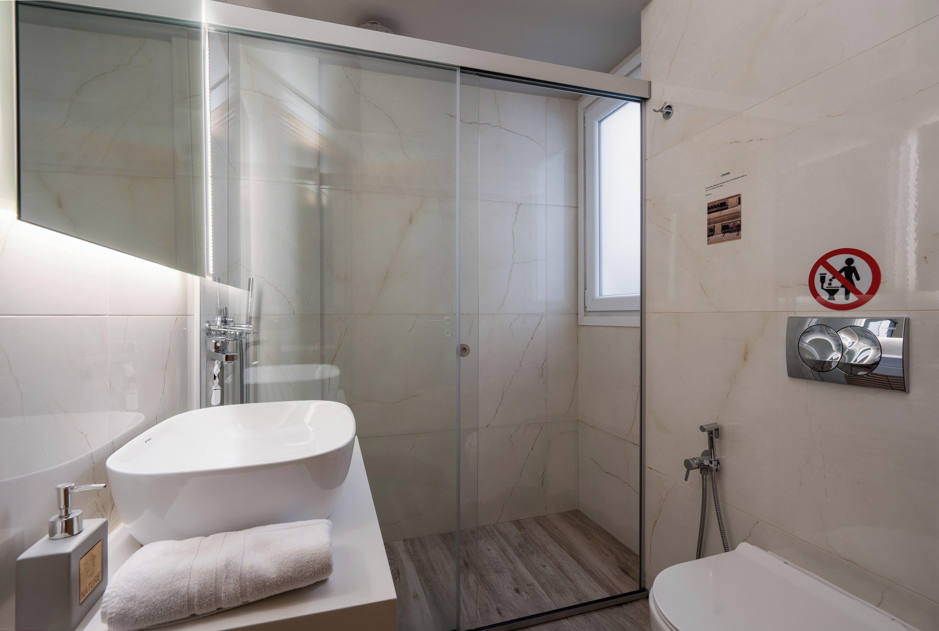 Un bany modern amb un envàs de dutxa de vidre, una banyera blanca i un vàter.