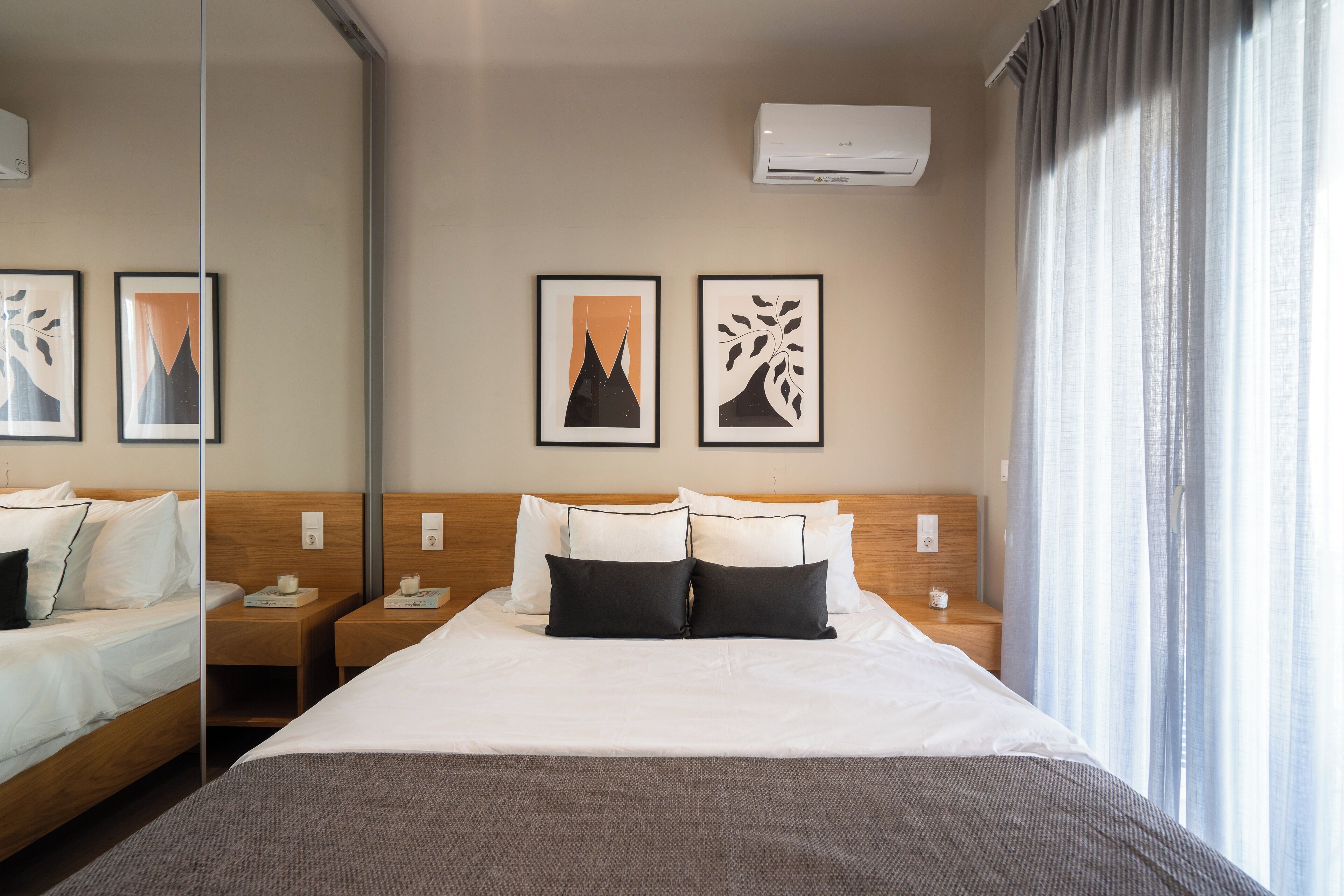 A hotel room with a large bed, two bedside tables, a mirror, and artwork on the wall.