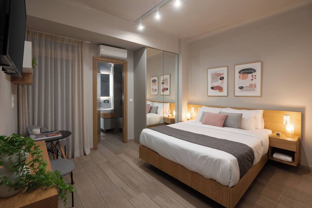 Ein modernes Schlafzimmer mit einem großen Bett, Nachttischen, einem Spiegel und Kunstwerken an der Wand.