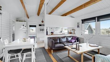 En moderne, åben planløsning med spiseplads, sofa og køkken.