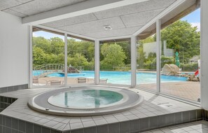 Ein Wellnessbereich mit Whirlpool und Blick auf ein Schwimmbad im Freien.