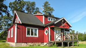 Une maison en bois rouge avec un balcon, une cheminée et un petit porche.