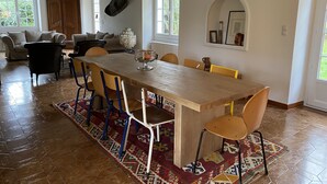 A spacious dining area with a long wooden table, multiple chairs, and a patterned rug. - Family home, its park and streams, on the route des Châteaux (Huisseau-sur-Mauves)