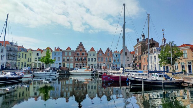 A marina with boats docked, surrounded by colorful buildings with traditional architecture. - Nice home in Heinkenszand with sauna (Heinkenszand)