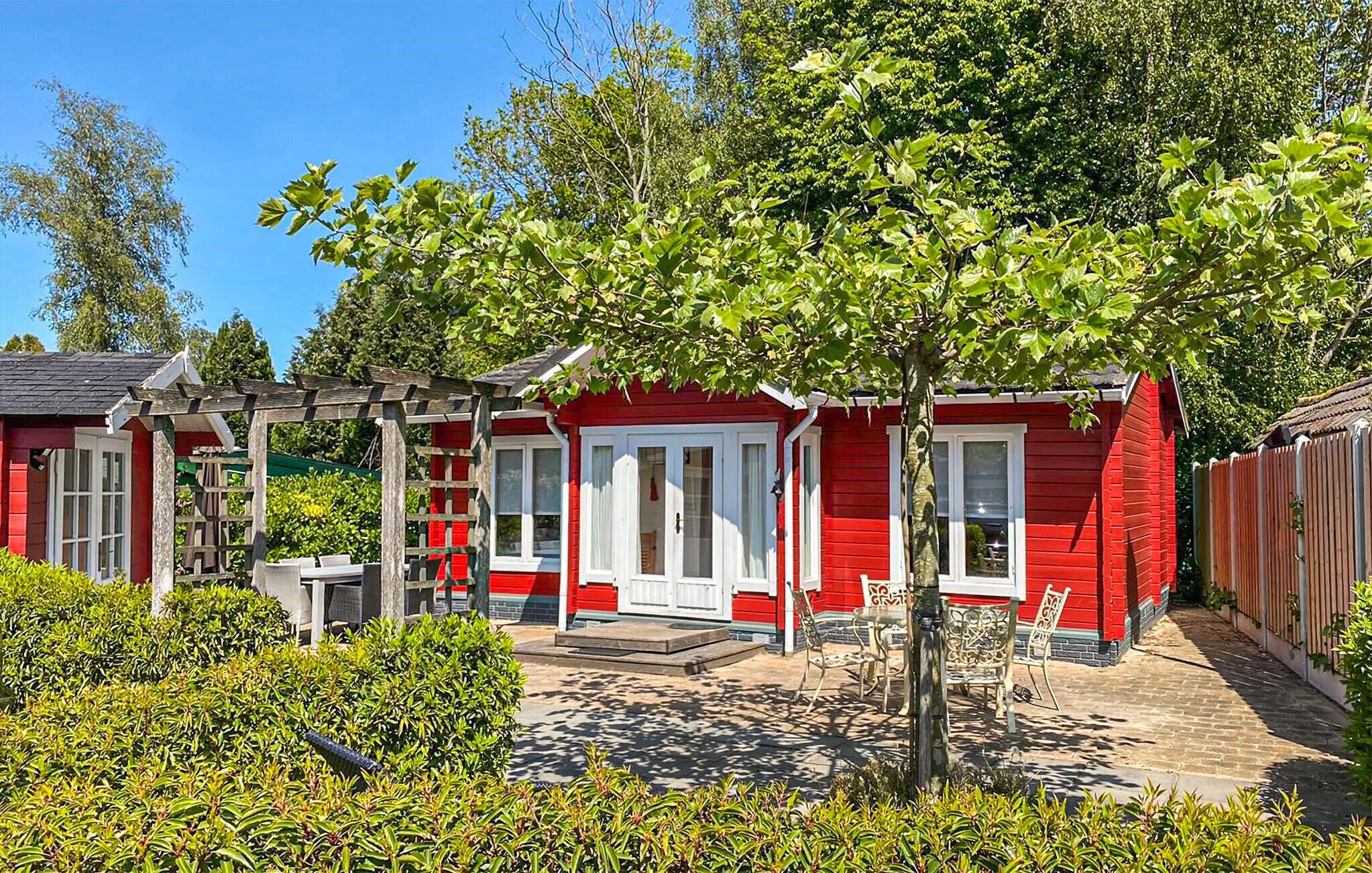 Un bâtiment rouge doté d’un patio couvert, entouré de verdure et d’arbres.