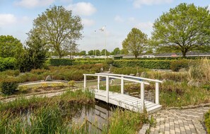 A serene park with a wooden bridge, a pond, and a dining area in the background. - Gorgeous home in Fredericia with WiFi (Fredericia)