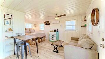 Un espacio habitable compacto con kitchenette, comedor y zona de estar.