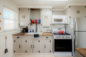 A kitchen with white cabinets, a microwave, a stove, and a refrigerator.
