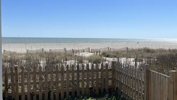 A wooden fence with a view of a beach and ocean.