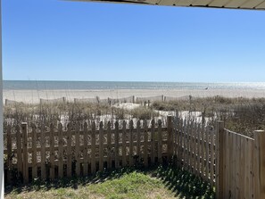 A wooden fence with a view of a beach and ocean.
