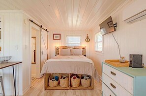 A bedroom with a bed, bedside table, wall-mounted TV, and a dresser.
