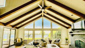 Un salon spacieux avec un haut plafond, de grandes fenêtres, une cheminée et un ventilateur de plafond.