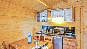 Una cucina compatta con pareti in legno, un tavolo da pranzo con sedie e un forno a microonde integrato.