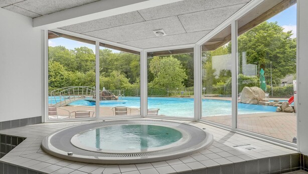 A spa area with a hot tub and a view of an outdoor pool.
