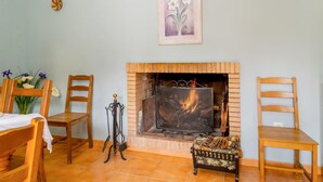 A cozy room with a fireplace, wooden furniture, and a framed artwork on the wall. - Nice home in Cortegana (Cortegana)
