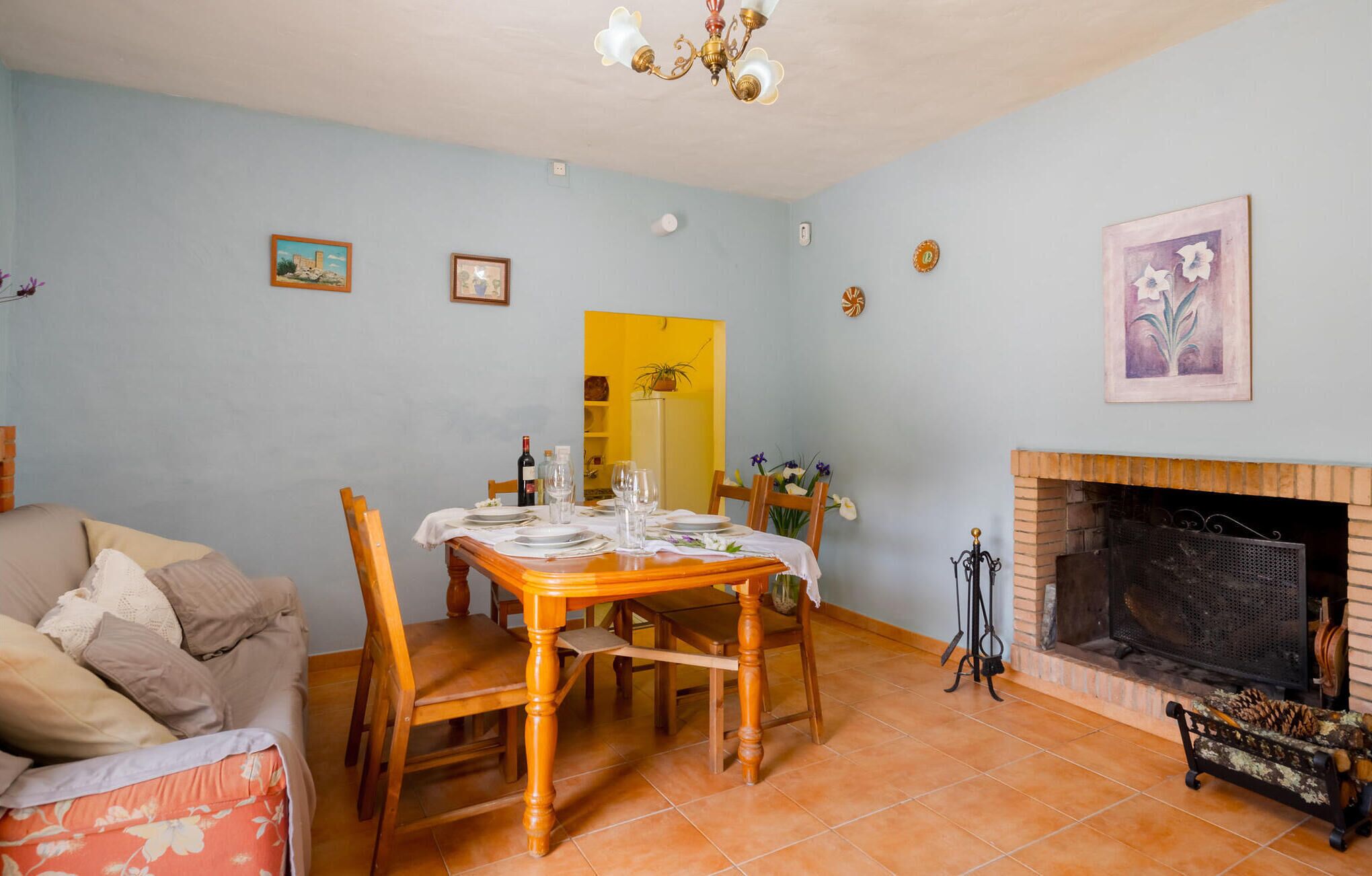 A dining area with a table set for four, a fireplace, and a sofa in a room with light blue walls.