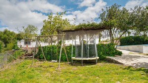 A backyard with a trampoline, a swing set, and a small shed. - Nice home in Cortegana (Cortegana)