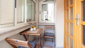 A small, cozy outdoor seating area with a wooden table and chairs, a potted plant, and a window with blinds. - Nice apartment in Sinj with WiFi (Sinj)