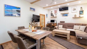 A modern living room with a wooden dining table, leather chairs, a brown sofa, and a ceiling fan. - Nice apartment in Sinj with WiFi (Sinj)