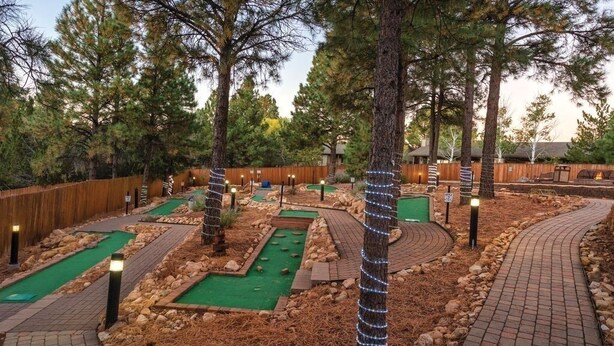 A miniature golf course with multiple holes, surrounded by trees and a wooden fence. - Price REDUCED  2Bed 2Bath, Full Kitchen & dining area, Washer/Dryer. Golf nearby (Flagstaff)