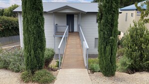 A residential building with a wooden deck leading to a front door, surrounded by tall evergreen trees and a gravel pathway. - Views, space and tranquility with bay and beach close by (Encounter Bay)