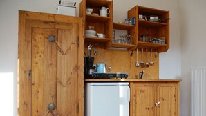 Cuina amb armaris de fusta, nevera blanca i diversos utensilis i aparells de cuina.