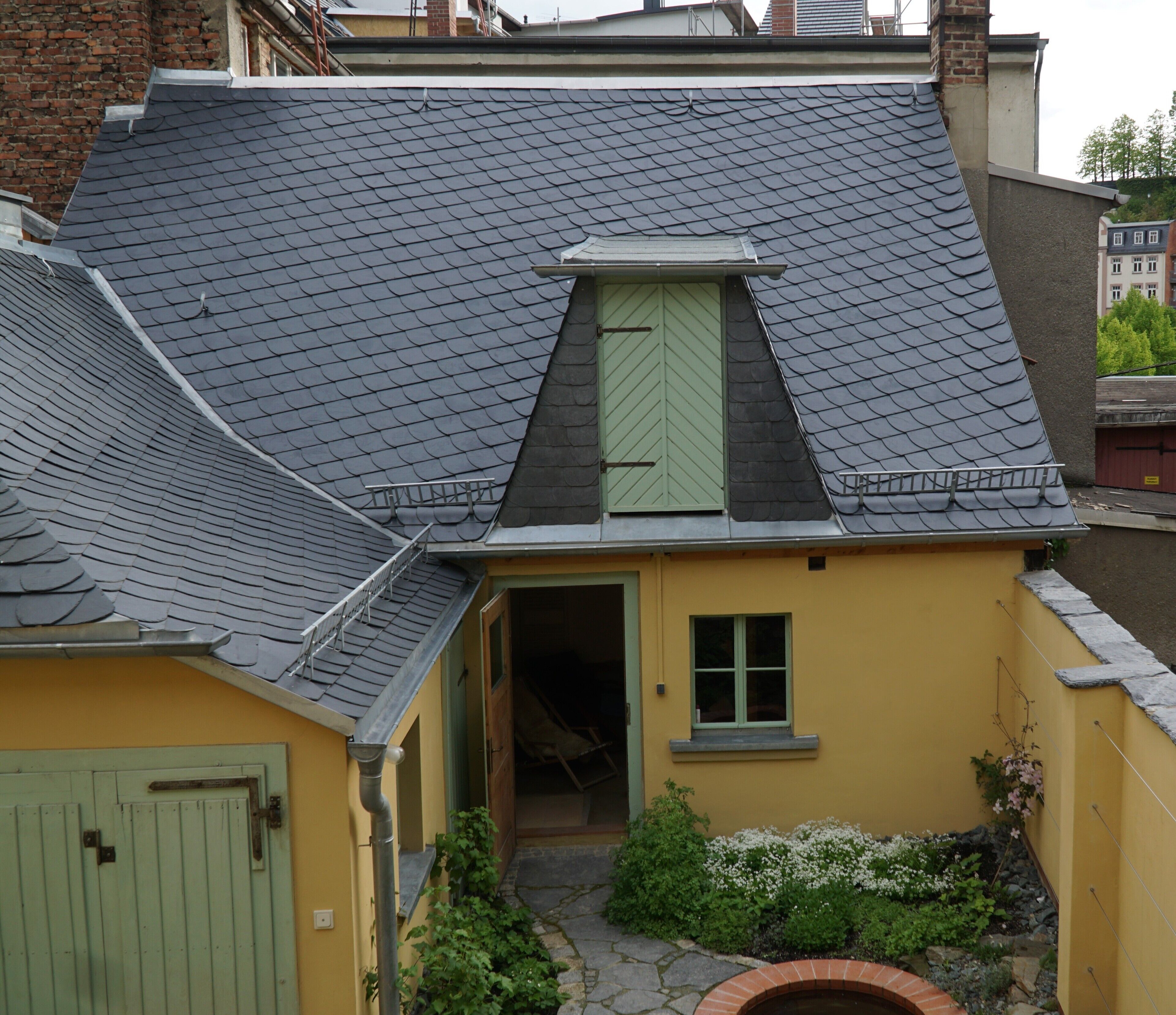 Un bâtiment jaune avec un toit en pente, une petite fenêtre et une porte.
