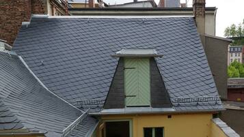 Un bâtiment jaune avec un toit en pente, une petite fenêtre et une porte.