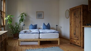 Un dormitori acollidor amb un llit de fusta, una planta en test, un escriptori i un armari.