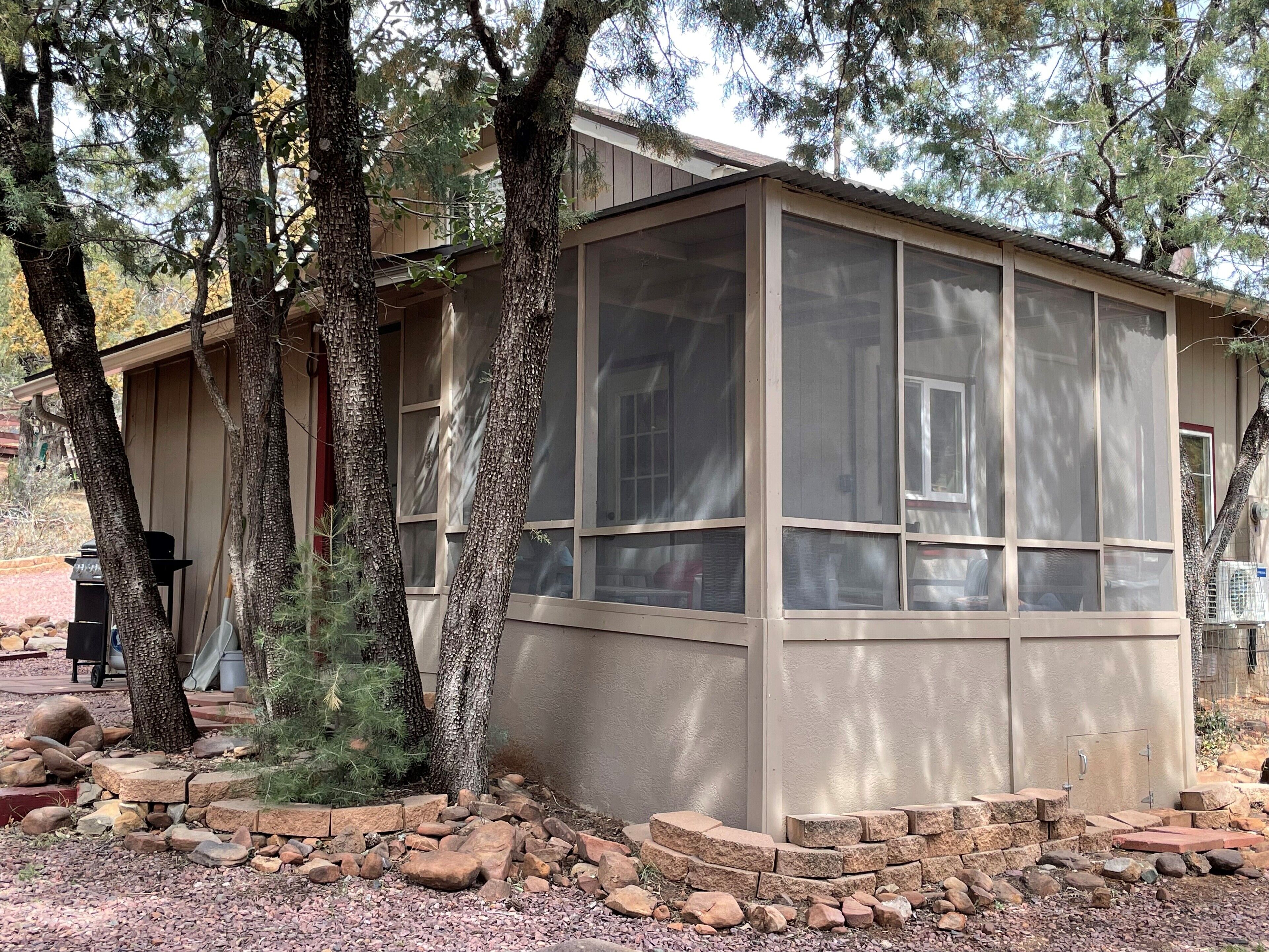 A building with a large window, surrounded by trees and a gravel path.