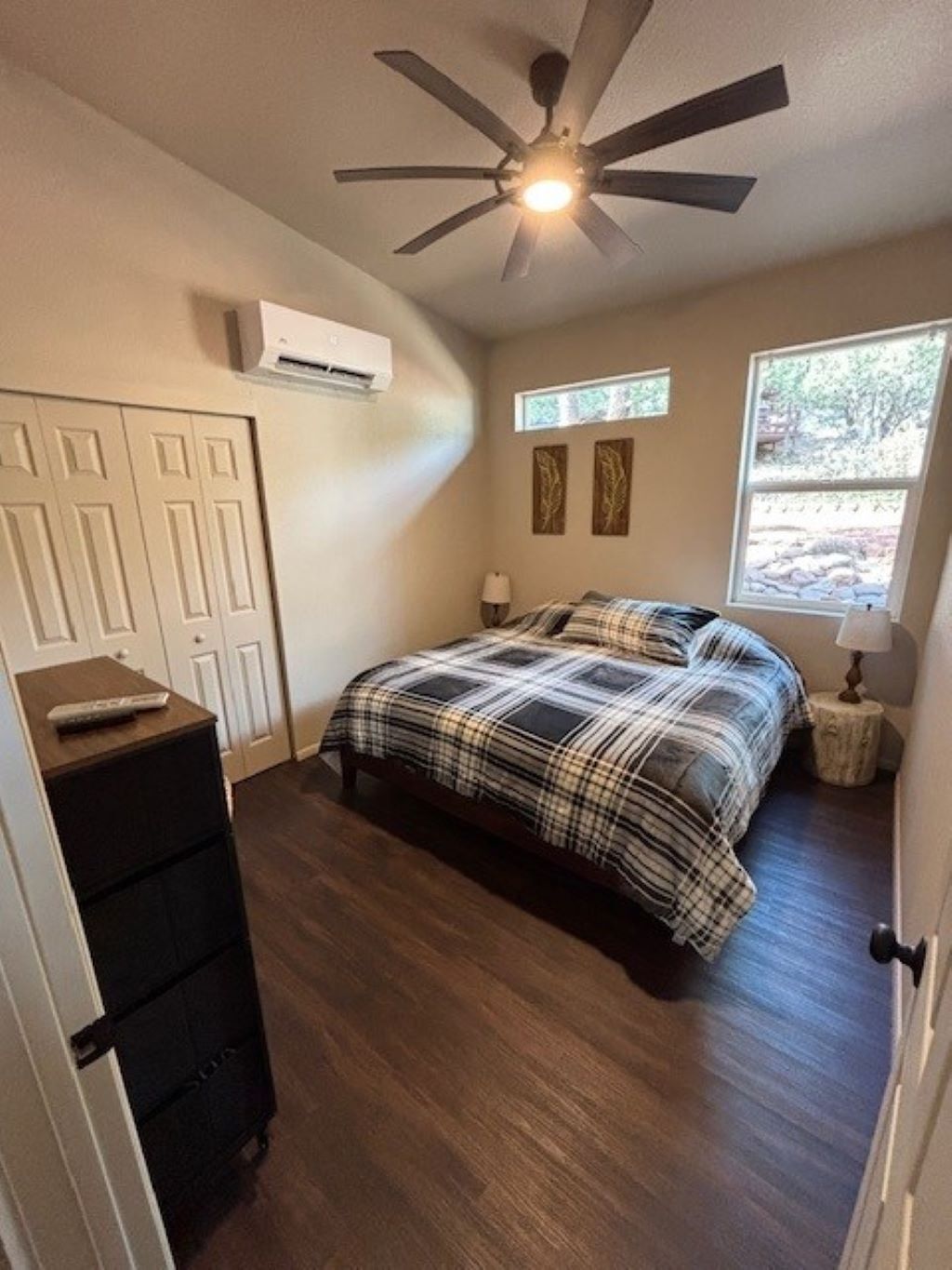 A bedroom with a bed, a ceiling fan, a window, and a dresser.